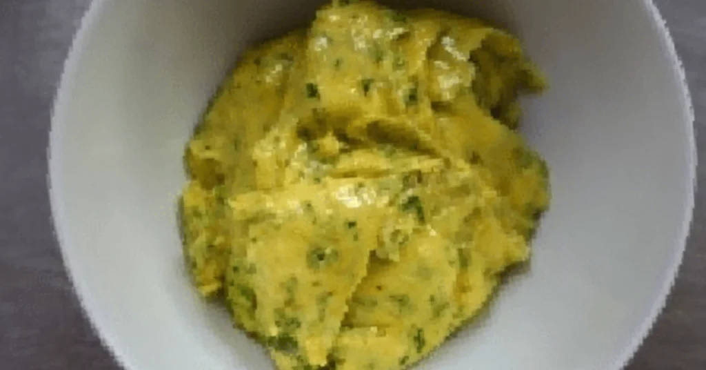 Herb butter or flavoured spread mixed with fresh green herbs, served in a white bowl.