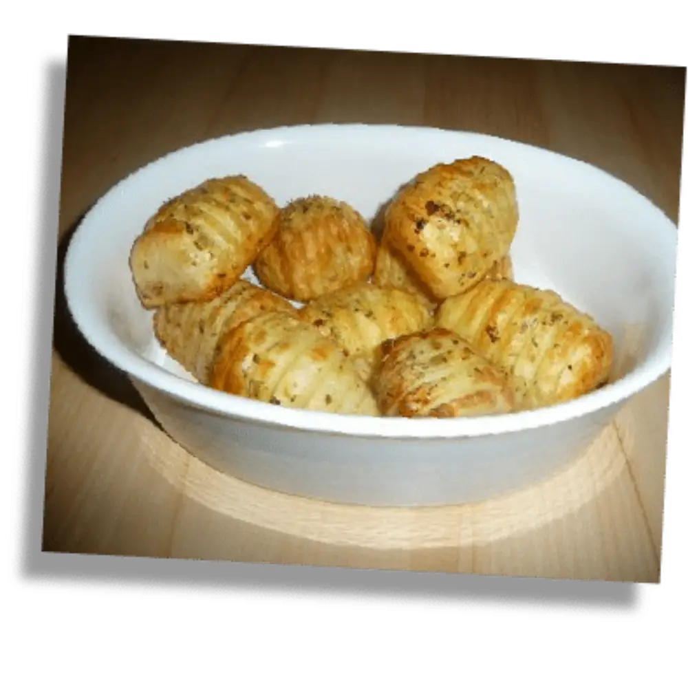 Crispy roasted hasselback potatoes served in a white bowl, seasoned with herbs and golden rapeseed oil.