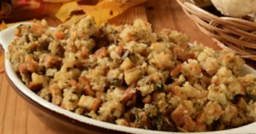 Homemade stuffing with herbs, carrots and breadcrumbs served in a white dish on a wooden table.