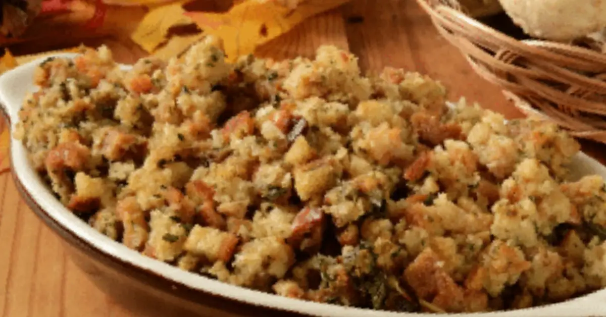Homemade stuffing with herbs, carrots and breadcrumbs served in a white dish on a wooden table.