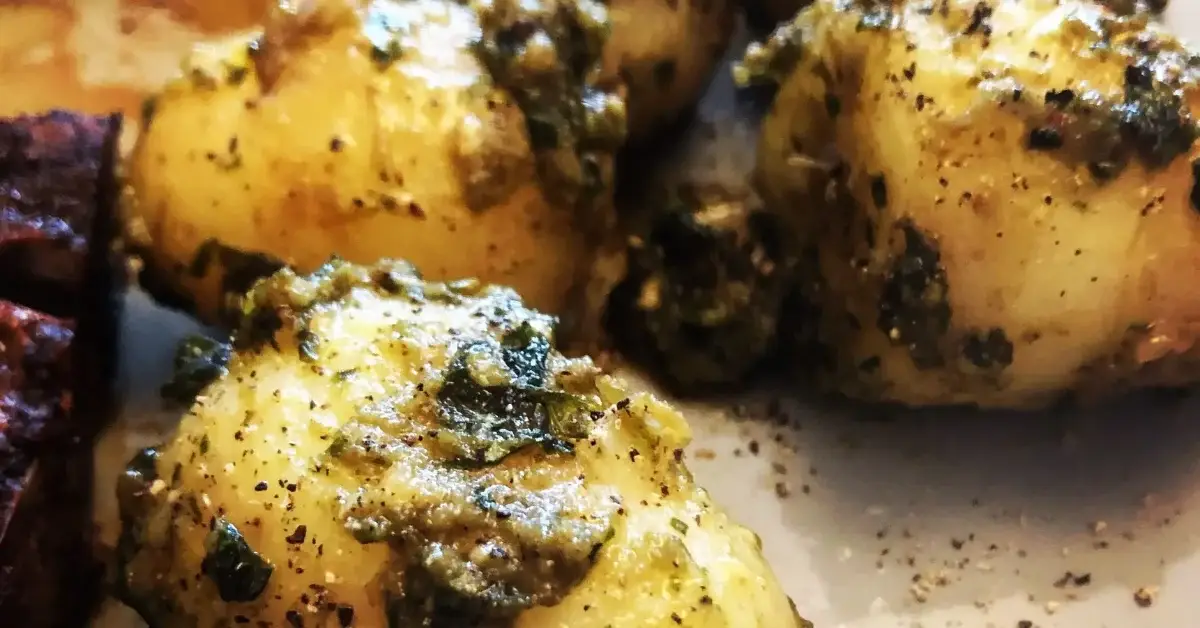 Close up of roasted new potatoes coated in herb dressing and seasoning.
