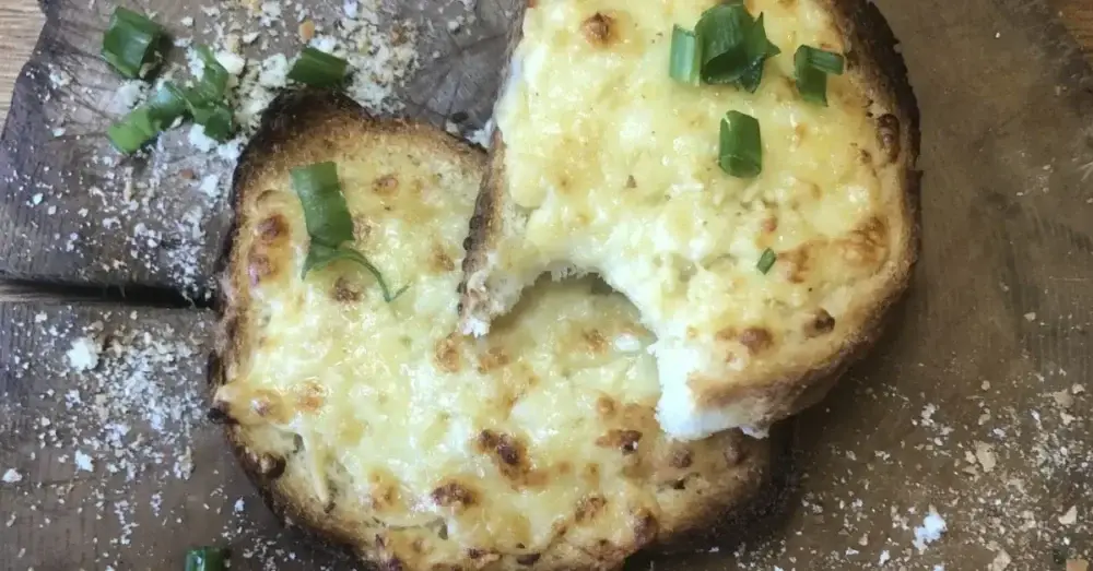 Cheesy toasted bread topped with spring onions on a wooden board
