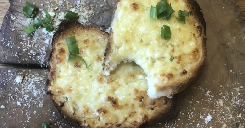 Cheesy toasted bread topped with spring onions on a wooden board