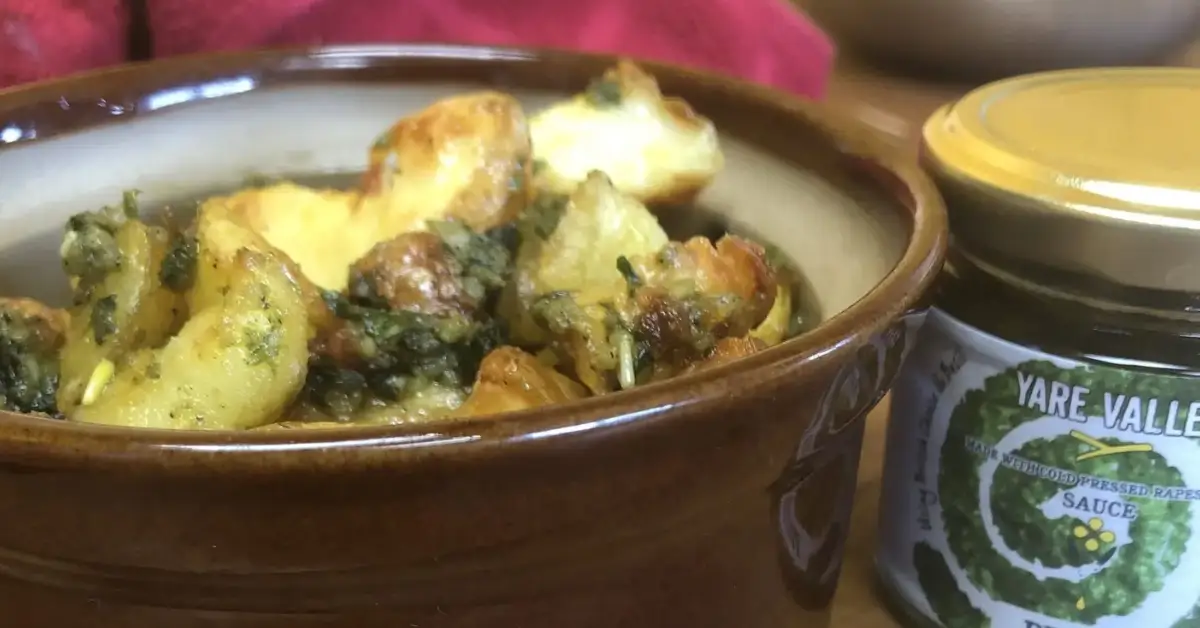 Roasted potatoes served in a bowl beside a jar of Yare Valley sauce