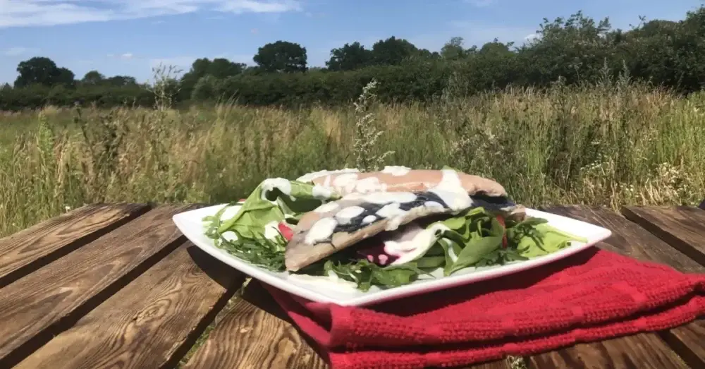 Fresh salad plate served outdoors on a wooden table beside a field