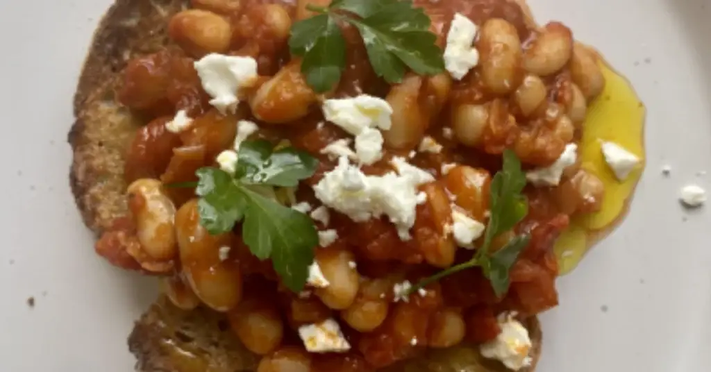Beans in a rich tomato sauce served on toast with crumbled cheese, parsley and a drizzle of Yare Valley rapeseed oil.