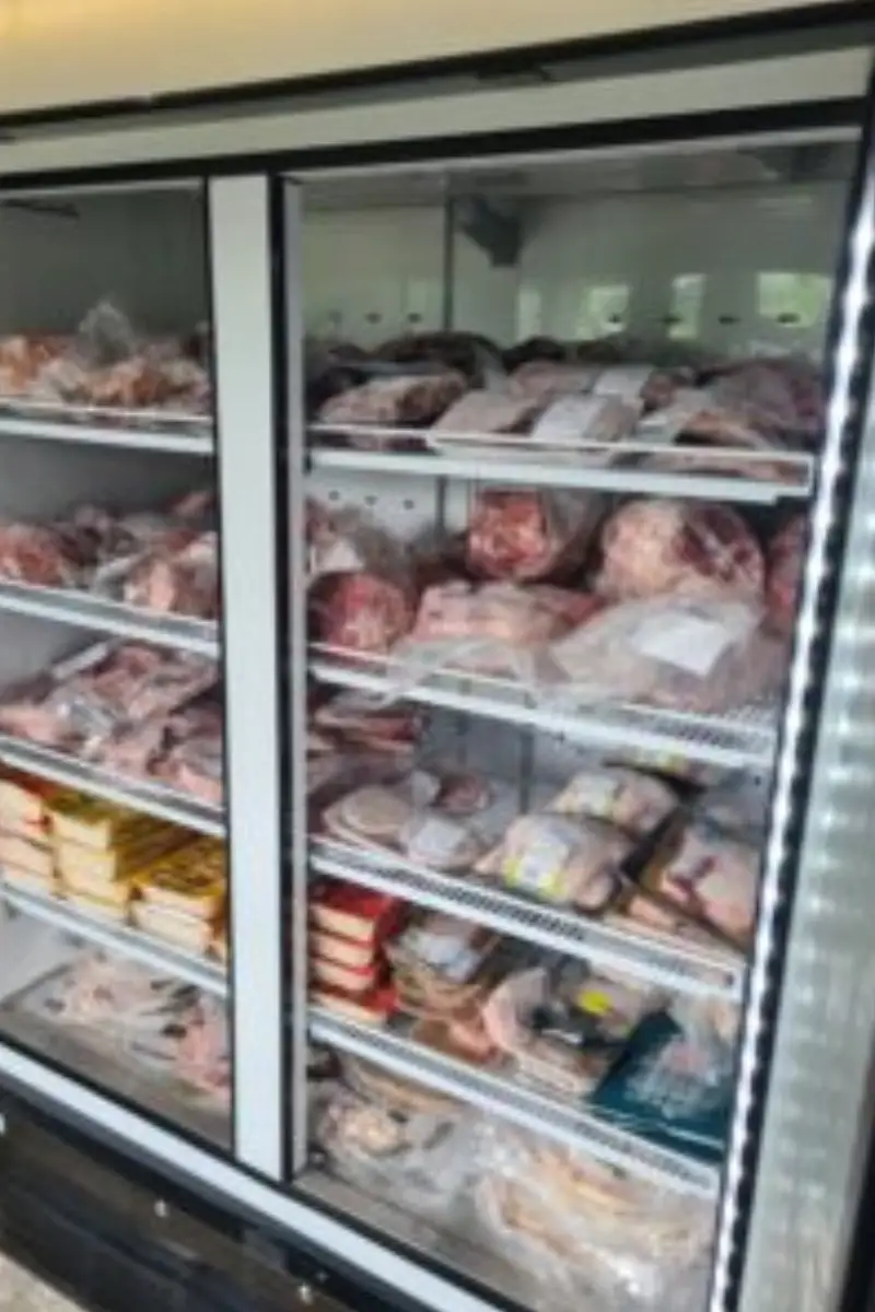Display freezer filled with packaged local meat products inside a farm shop.
