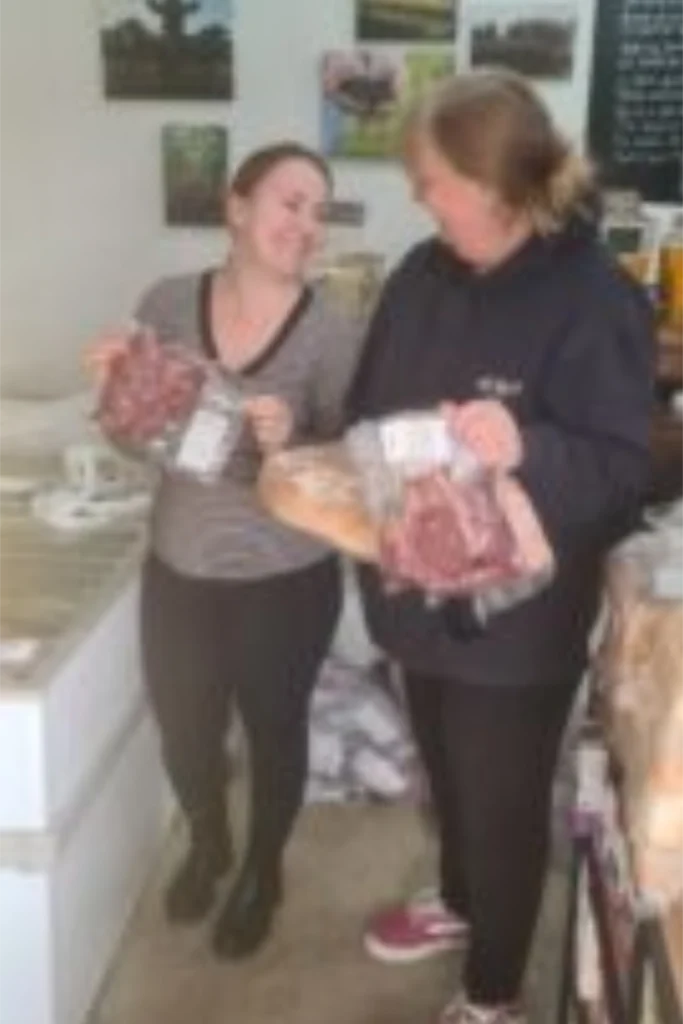 Two people holding bags of farm shop produce inside the Yare Valley farm shop.