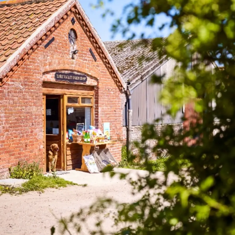 Yare Valley farm shop entrance in a brick building with local products displayed outside.