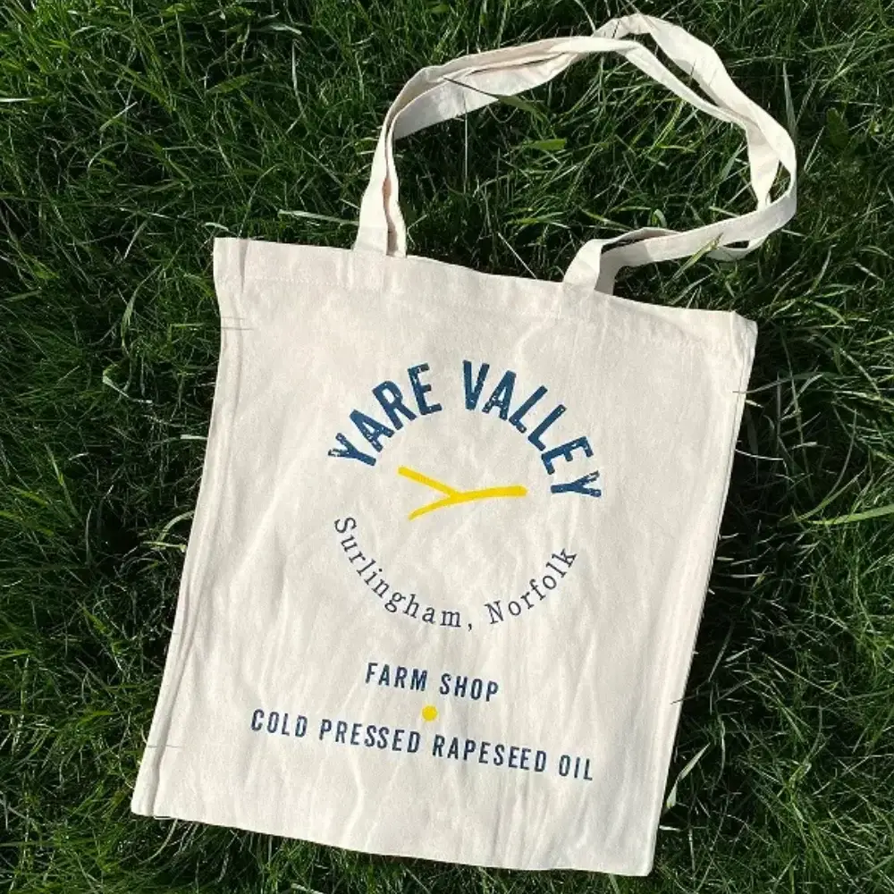 Yare Valley branded tote bag displayed on grass, featuring the farm shop and cold pressed rapeseed oil logo.
